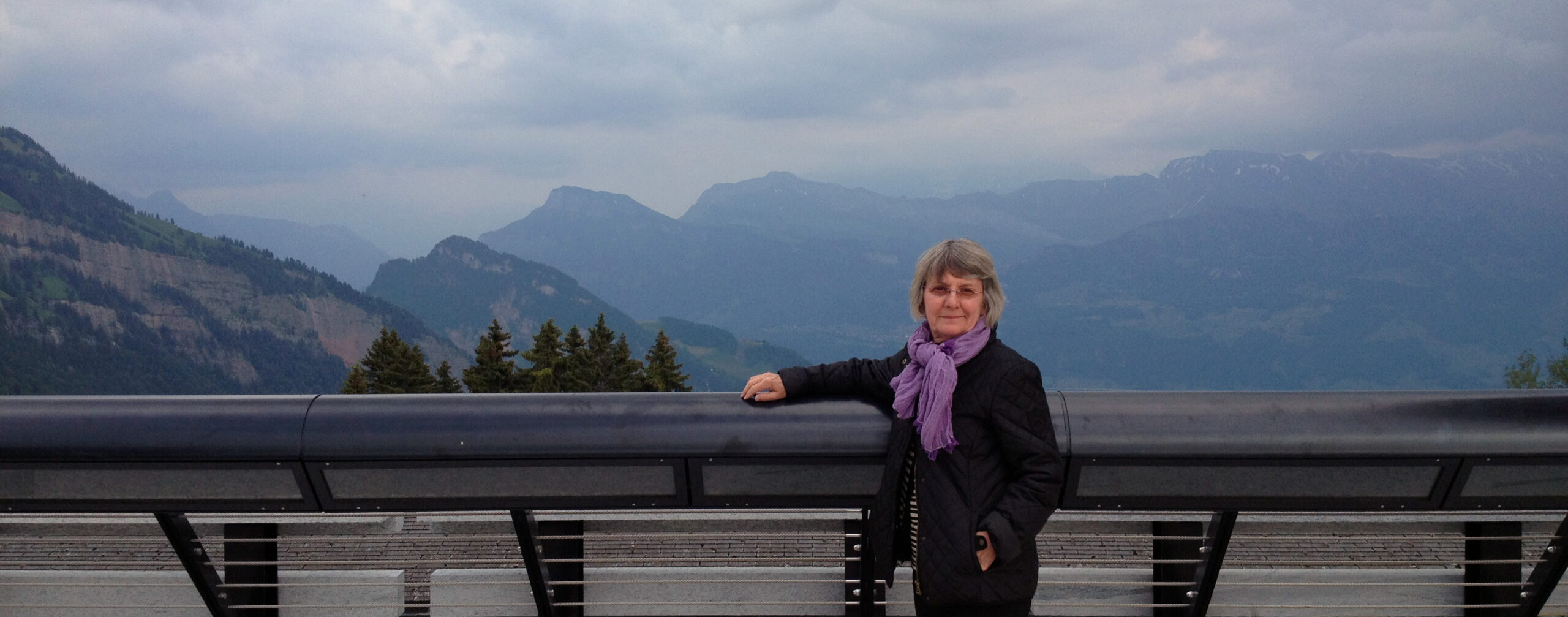 Donna Dunay in foreground with her arm resting on a railing and mountains in the background